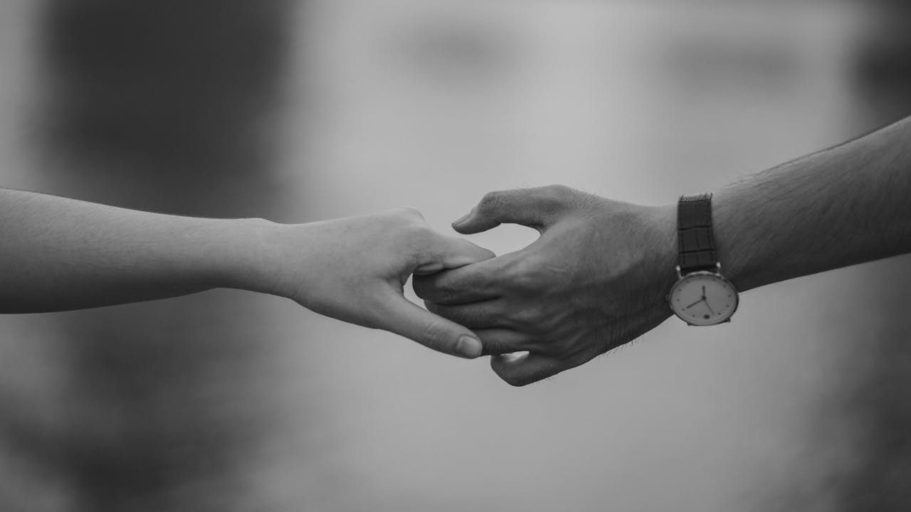 Monochrome image of two hands holding, symbolizing love and connection.