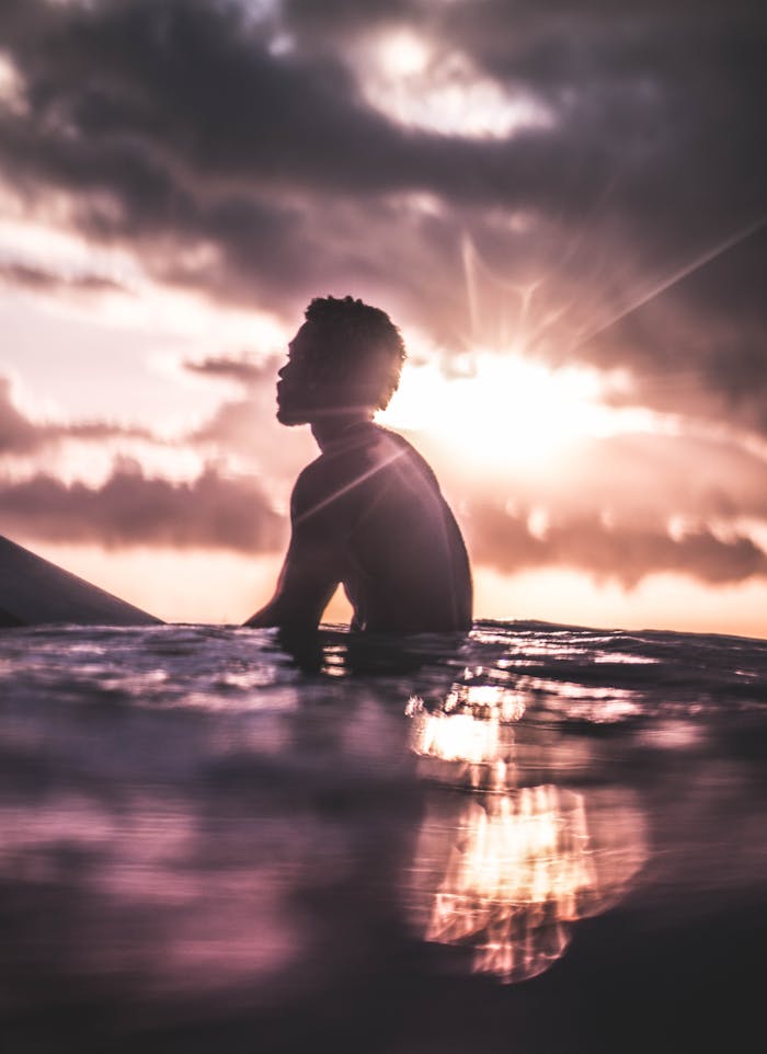 Silhouette of a serene surfer in the ocean at sunset, capturing a peaceful and idyllic moment.